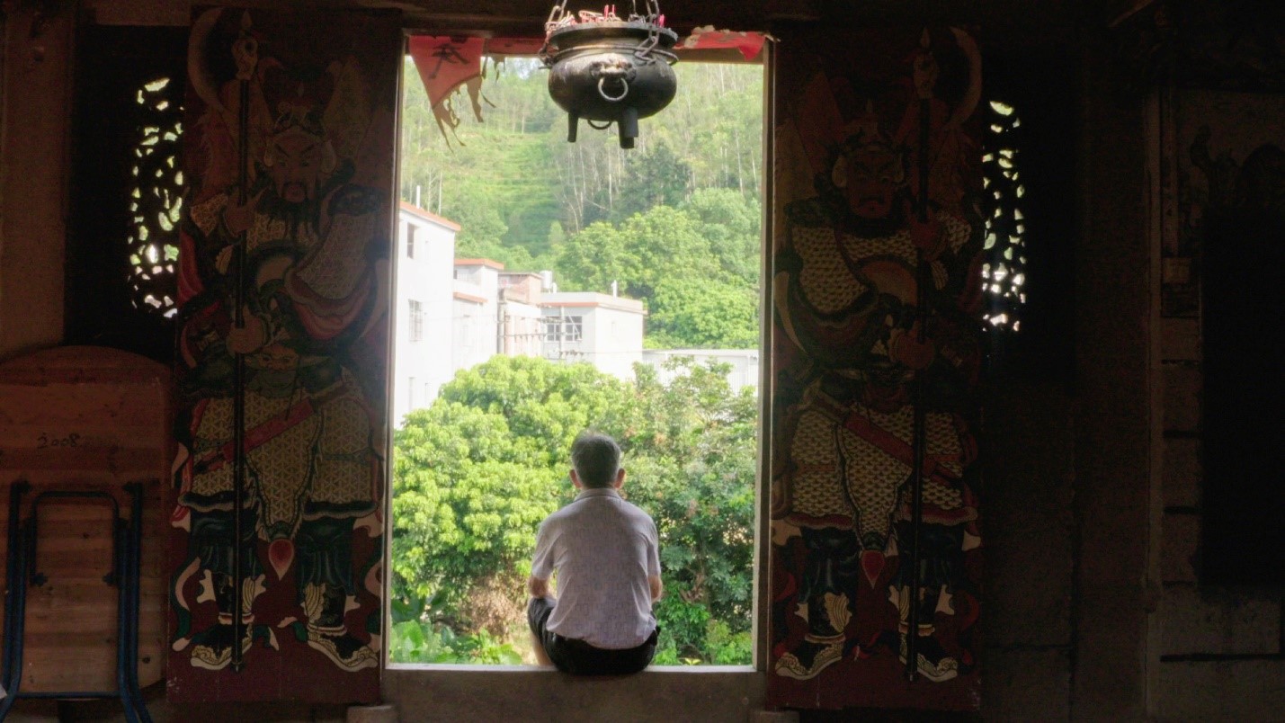 man sitting in temple doorway in rural China